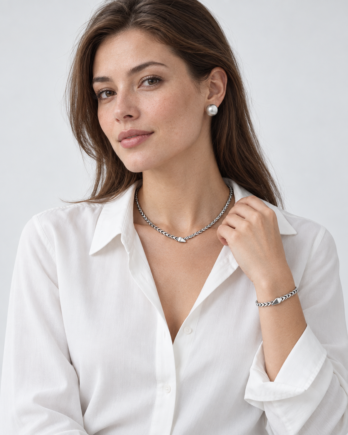Model wearing a silver necklace, matching earring and bracelet