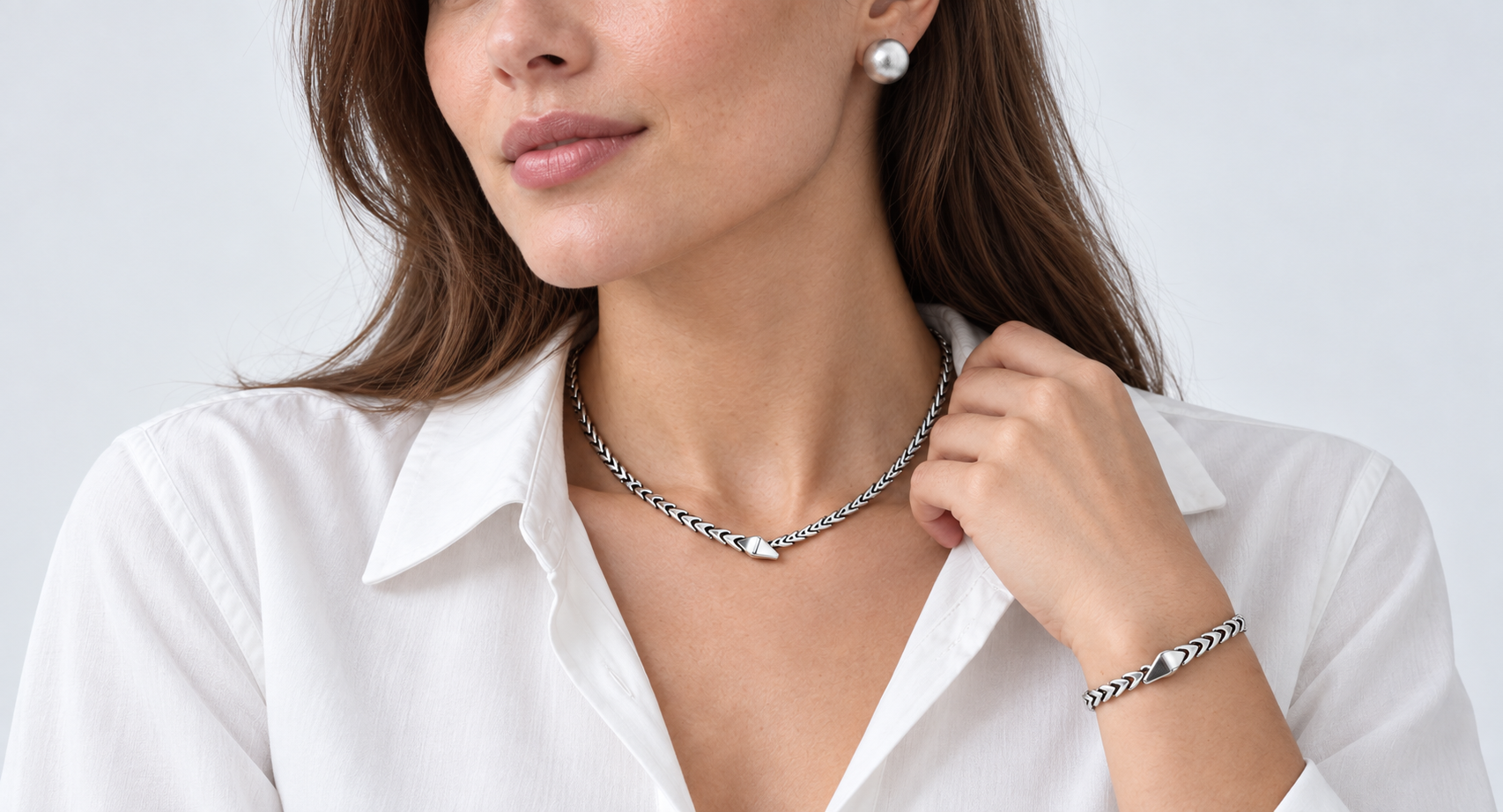 Model wearing a silver necklace, bracelet and brushed silver earrings